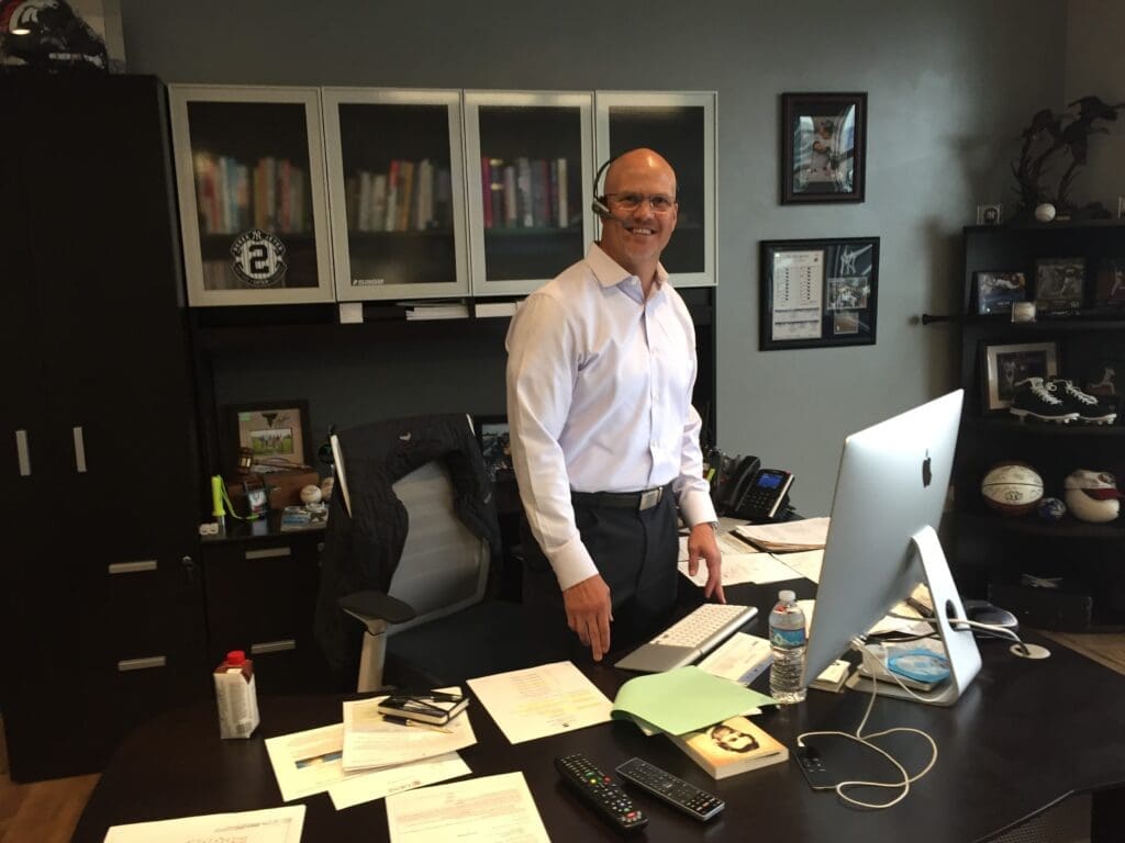Smiling businessman at desk in home office with computer, phone and documents for eCommerce logistics