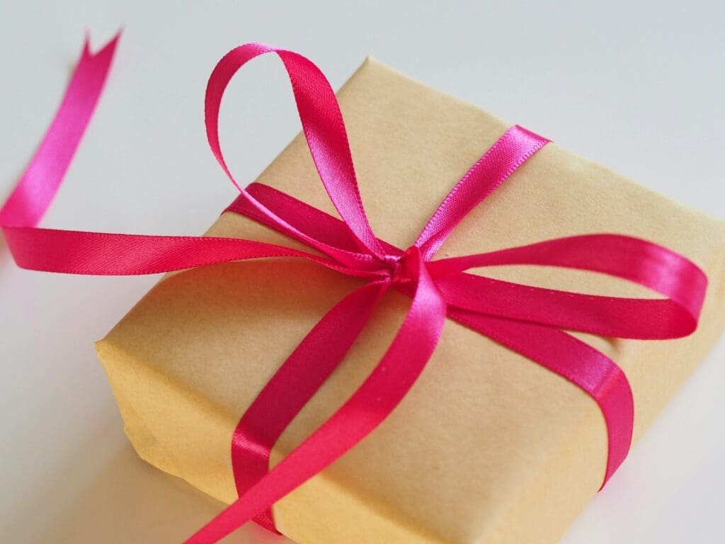 Gift box wrapped in kraft paper tied with a bright pink satin ribbon bow