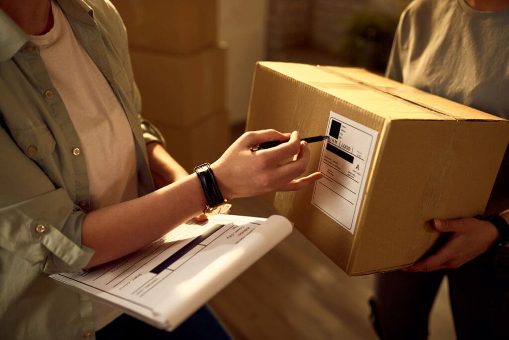Hands writing on shipping label while holding package, eCommerce order fulfillment