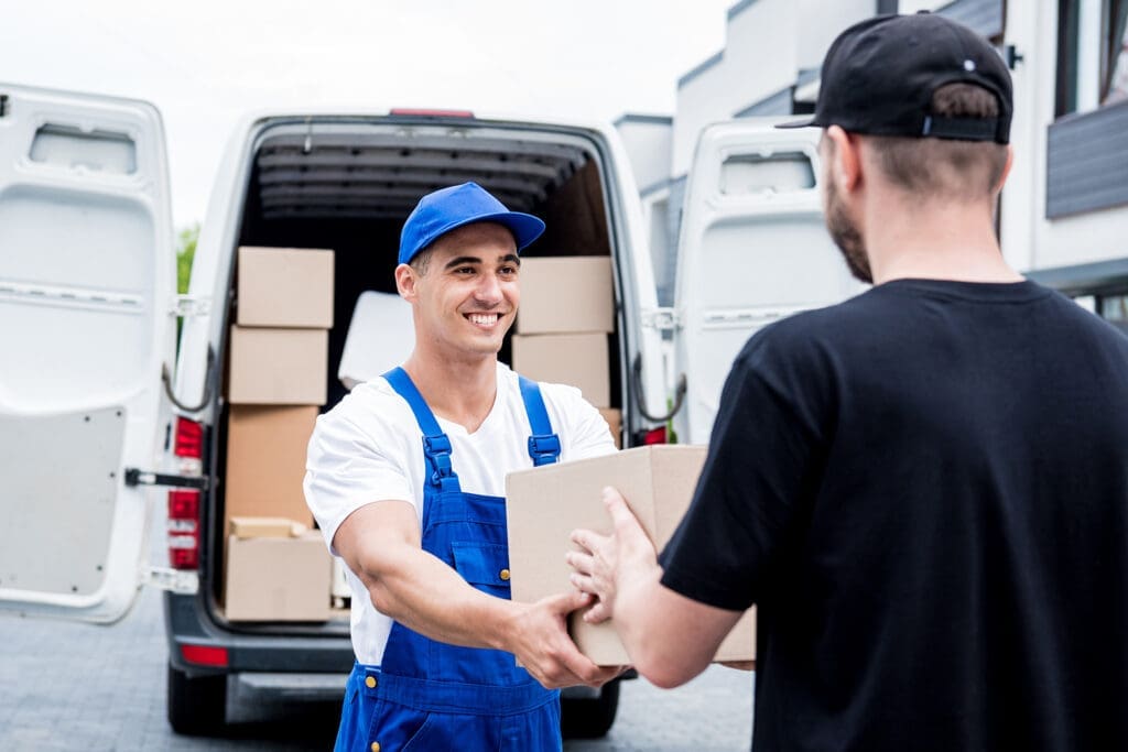 Friendly delivery driver handing package to customer from van, smiling at camera