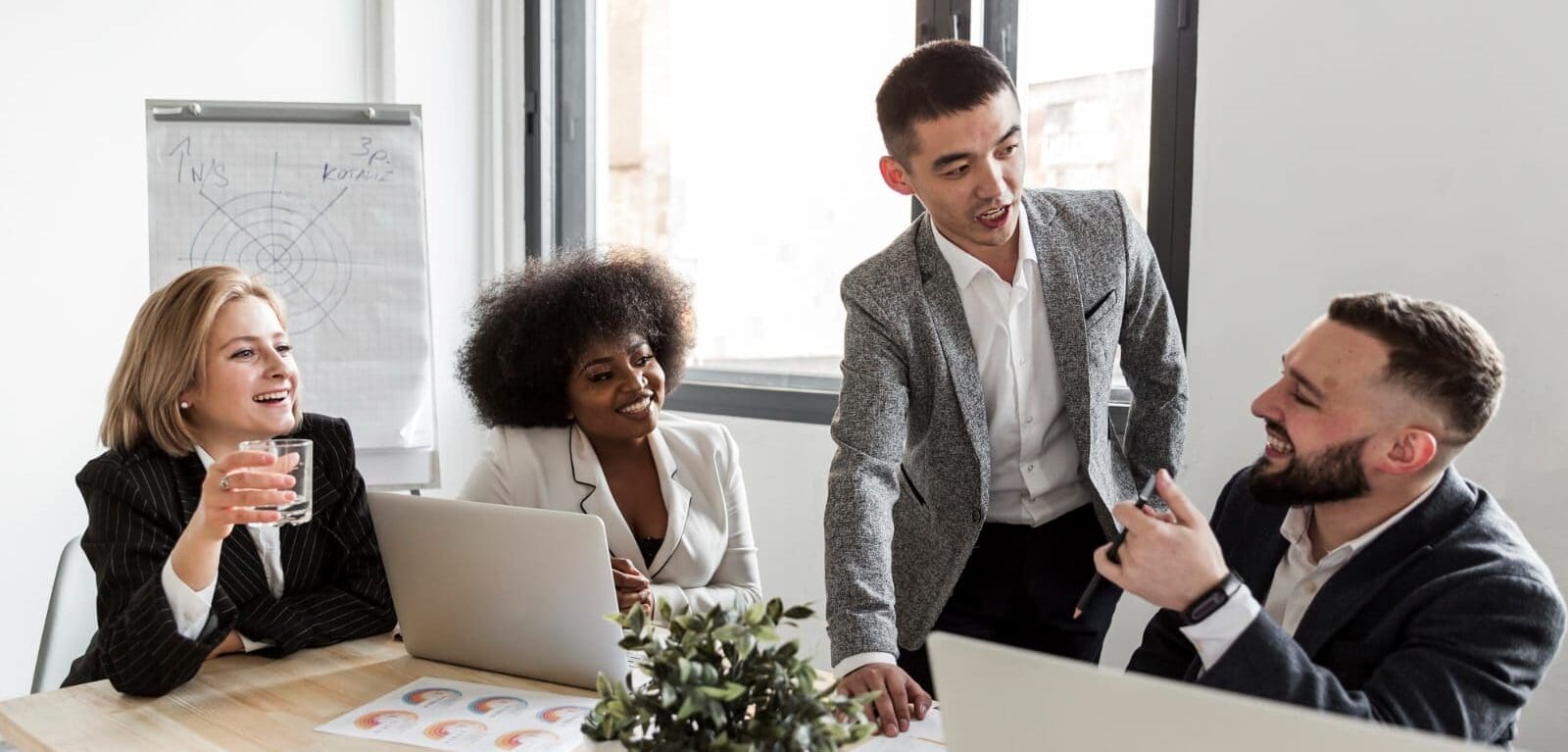 Group of diverse business colleagues laughing together while working at office meeting table
