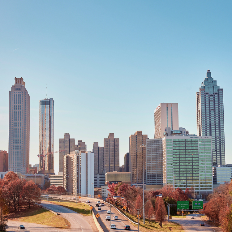 Atlanta skyline with high-rise buildings, highways and autumn foliage under a clear blue sky