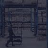 Man walking through warehouse shelving stocked with boxes