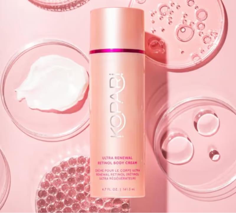 Pink Kopari Ultra Renewal Retinol Body Cream bottle and transparent containers on pink backdrop
