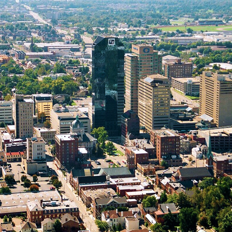 Aerial view of downtown buildings in a city with skyscrapers, trees and roads on a sunny day