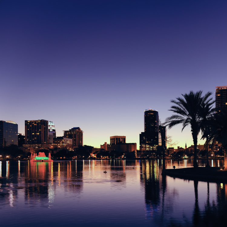 Orlando skyline at dusk reflecting in Lake Eola, with city lights and palm trees
