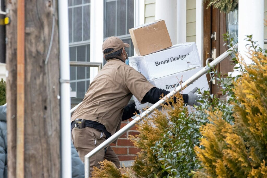 Deliveryperson in UPS uniform bringing boxes up steps