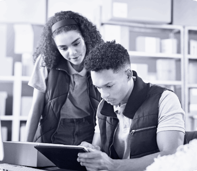 A photo of two people looking over a box and tablet
