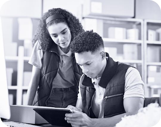 A photo of two people looking over a box and tablet